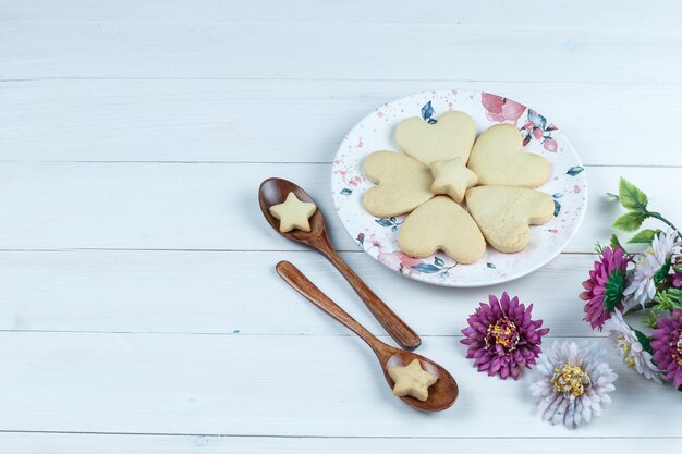 Hochwinkelansicht herzförmig und Sternplätzchen im weißen Teller mit Blumen