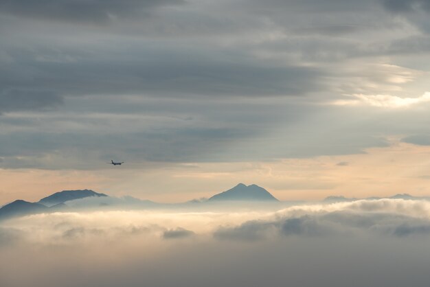 Hochwinkelaufnahme der schönen Berggipfel, die durch die Wolken und den Nebel sichtbar sind