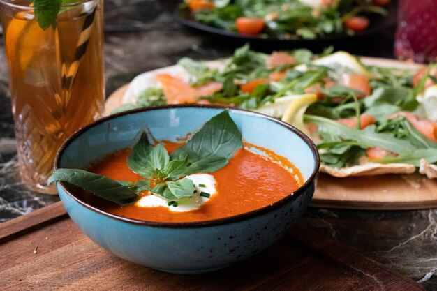 Hochwinkelaufnahme einer Schüssel Tomatensuppe und eines Tellers mit frischem Salat auf einem Tisch