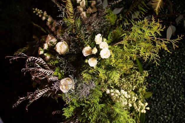 Hochwinkelaufnahme eines Blumenstraußes mit immergrünen Blättern und weißen Rosen unter den Lichtern