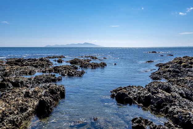 Hochwinkelaufnahme von Felsformationen im Wasser der Pukerua Bay in Neuseeland