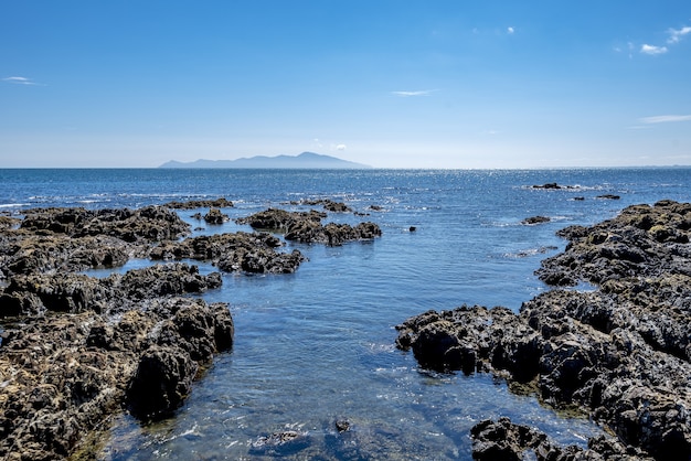 Hochwinkelaufnahme von Felsformationen im Wasser der Pukerua Bay in Neuseeland