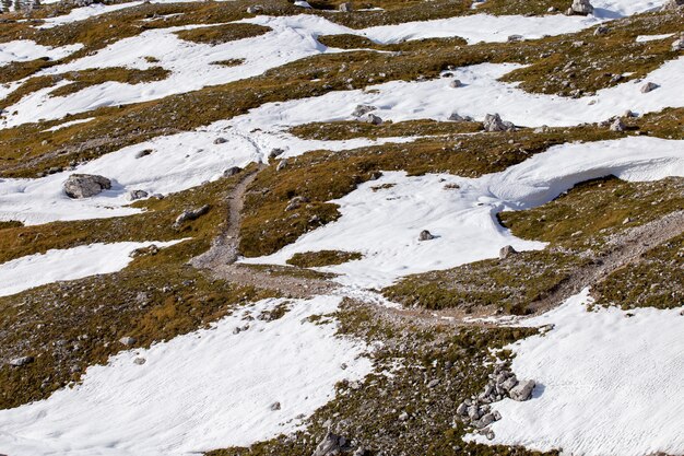 Hochwinkelaufnahme von Landtexturen, die teilweise mit Schnee in den italienischen Alpen bedeckt sind