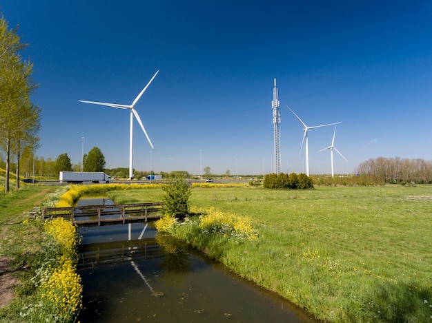 Hochwinkelaufnahme von Windkraftanlagen in der Nähe der in den Niederlanden eroberten Autobahnen und Wiesen