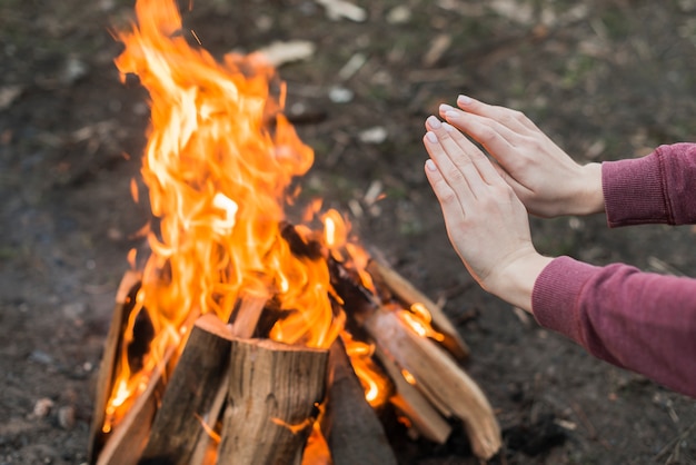 Hochwinkelfrau, die am Lagerfeuer wärmt