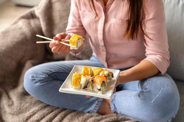 Hochwinkelige Frau, die zu Hause Sushi isst