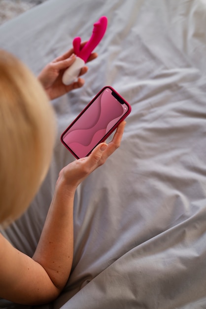 Hochwinkelige Frau mit Smartphone und Vibrator