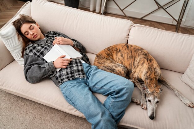 Hochwinkelige Frau und Hund, die auf der Couch schlafen