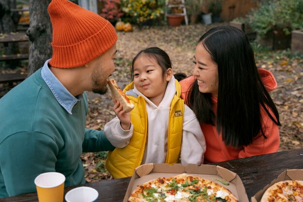 Hochwinkelige Smiley-Familie mit Pizza im Freien