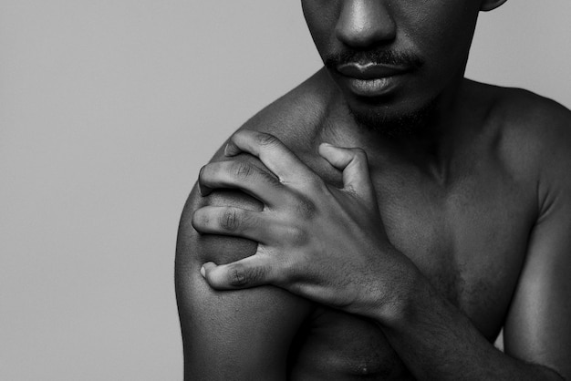 Kostenloses Foto hochwinkeliger nackter mann, der im studio schwarz-weiß posiert