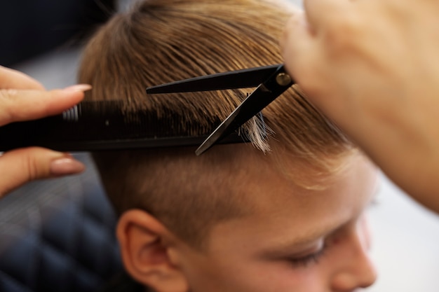 Kostenloses Foto hochwinkelkind, das im salon die haare schneidet