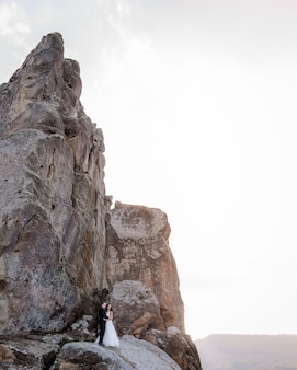 Hochzeitspaar steht in der nähe der hohen klippe und umarmt, hochzeitsreise, hochzeitsfoto