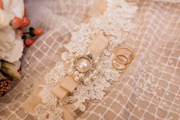 Hochzeitszubehör für eine Braut und Eheringe auf dem Hochzeitskleid