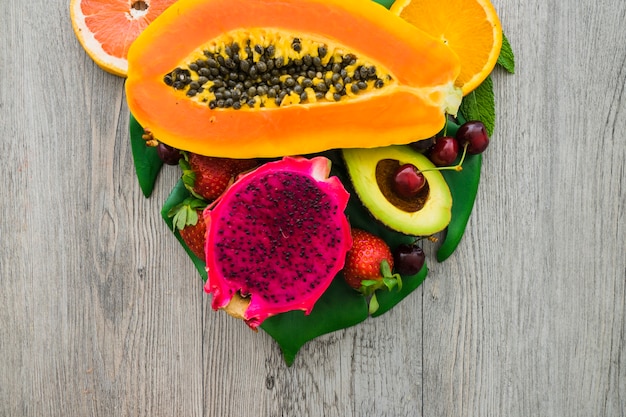 Hölzerne Oberfläche mit Drachenfrucht, Papaya und anderen Früchten