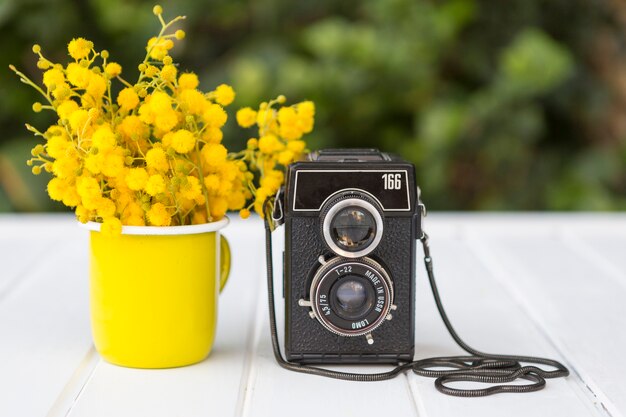 Hölzerne Oberfläche mit gelben Blumen und Vintage-Kamera