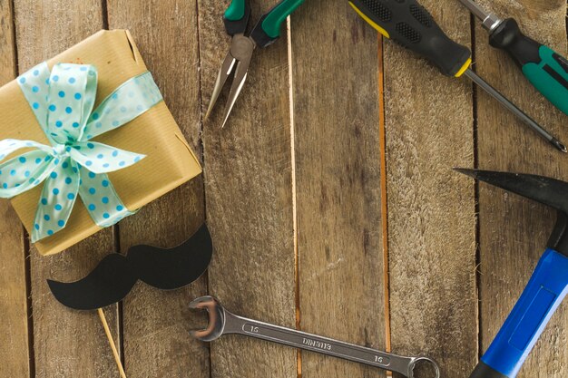 Hölzerne Oberfläche mit Werkzeugen und Geschenk für Vatertag