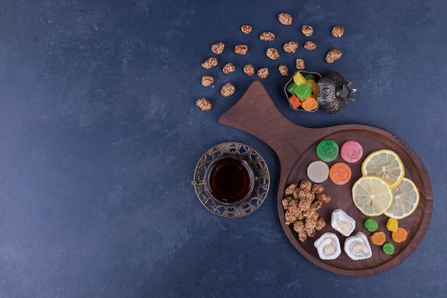 Hölzerne Snackplatte mit Marmeladen und einem Glas Tee in der Mitte