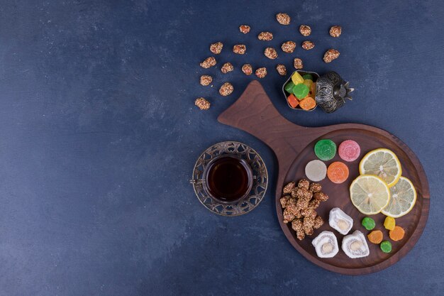 Hölzerne Snackplatte mit Marmeladen und einem Glas Tee in der Mitte