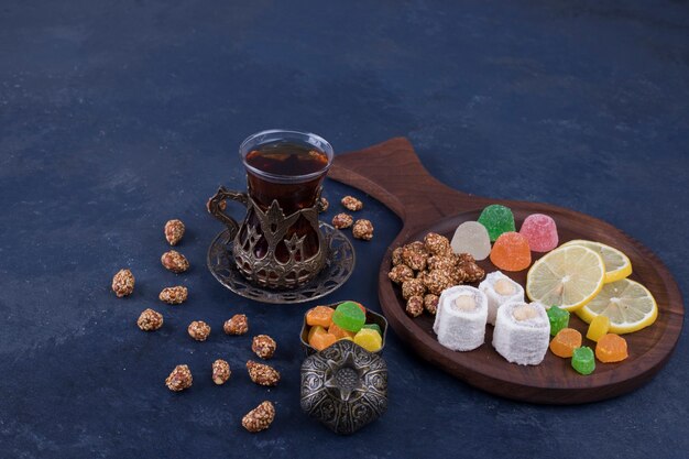 Hölzerne Snackplatte mit Marmeladen und einem Glas Tee