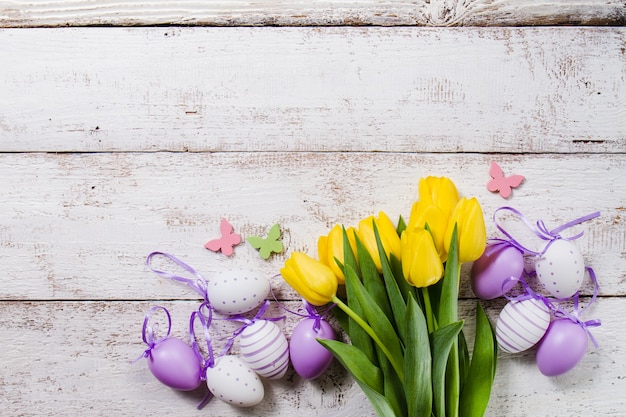 Kostenloses Foto hölzerner hintergrund mit gelben tulpen und ostereier