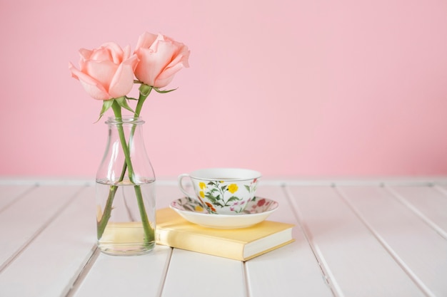 Hölzerner Hintergrund mit Vase, Kaffeetasse und Buch