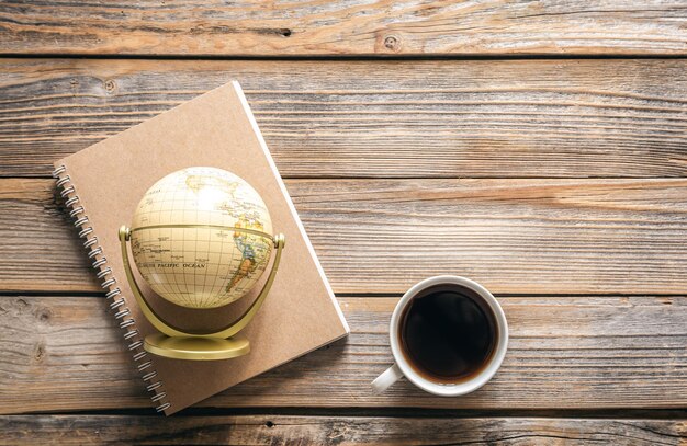 Kostenloses Foto hölzerner reisehintergrund mit globus-notizblock und kaffeetasse-draufsicht