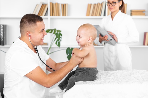 Hörendes entzückendes Baby jungen Doktors mit Stethoskop