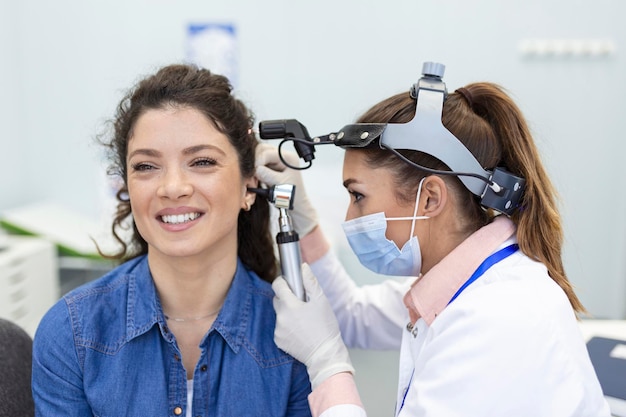 Höruntersuchung HNO-Arzt, der das Ohr der Frau mit Otoskop oder Auriskop in der medizinischen Klinik überprüft
