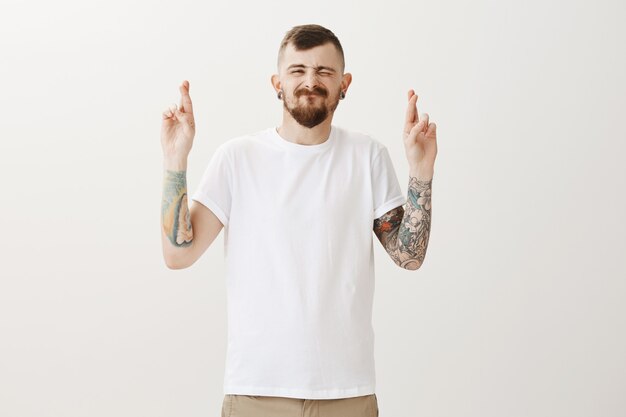 Hoffnungsvoll aufgeregt Hipster Kerl Daumen drücken viel Glück und Wunsch machen