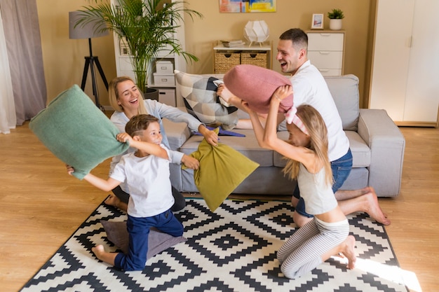 Hohe Ansichtfamilie, die mit Kissen spielt