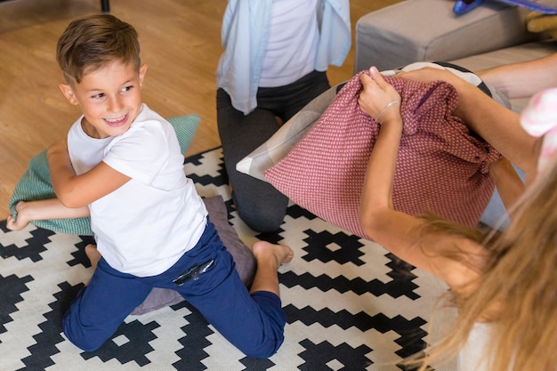 Hohe Ansichtkinder, die mit Kissen spielen