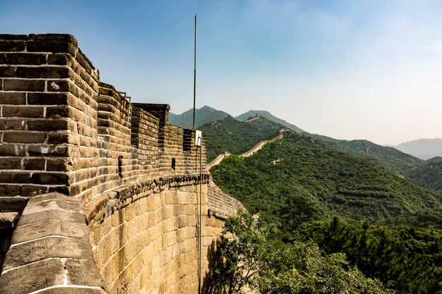 Hohe Winkel-Nahaufnahmeaufnahme der berühmten Chinesischen Mauer, umgeben von grünen Bäumen im Sommer