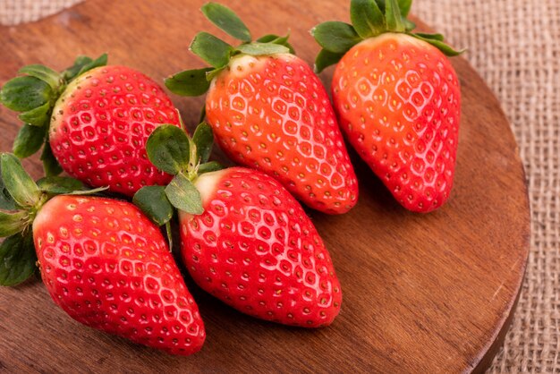 Hohe Winkel-Nahaufnahmeaufnahme von frischen Erdbeeren auf einem runden hölzernen Schreibtisch