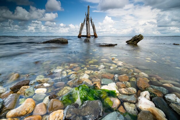 Hohe Winkel-Nahaufnahmeaufnahme von Steinen an der Küste mit dem ruhigen Meer auf dem Hintergrund