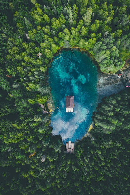 Hohe Winkelansicht eines Gebäudes in einem See, umgeben von Wäldern unter einem bewölkten Himmel