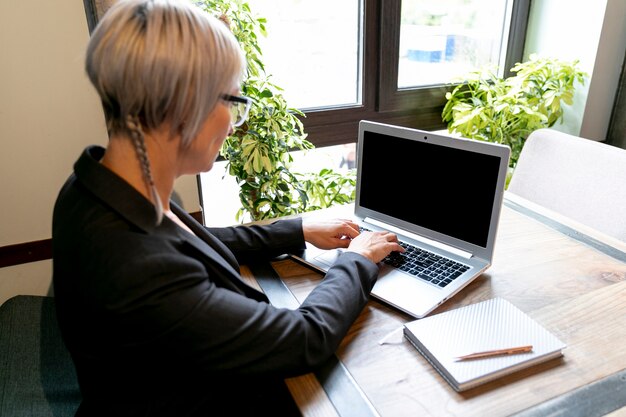 Hohe WinkelGeschäftsfrau, die an Laptop arbeitet