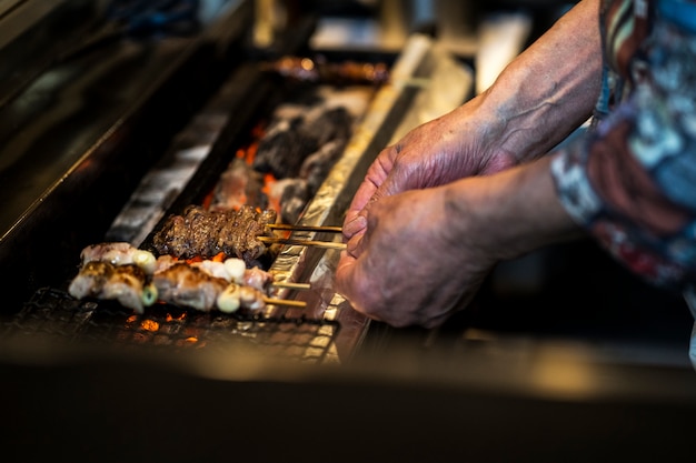 Hohe Winkelhände, die japanisches Straßenessen kochen