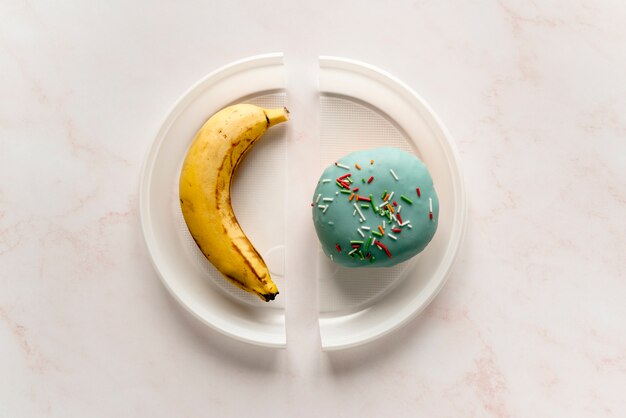 Hohe Winkelsicht der Banane und des Donuts auf defekter Platte