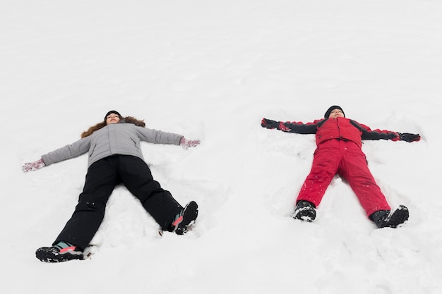 Hohe Winkelsicht des Bruders und der Schwester, die auf Schnee liegen