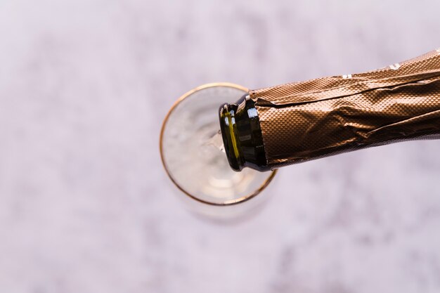 Hohe Winkelsicht des Champagners gießend in das Glas auf unscharfem Hintergrund