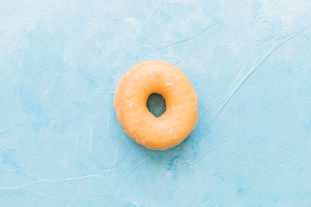 Hohe Winkelsicht des geschmackvollen glasig-glänzenden Donuts auf blauem Hintergrund