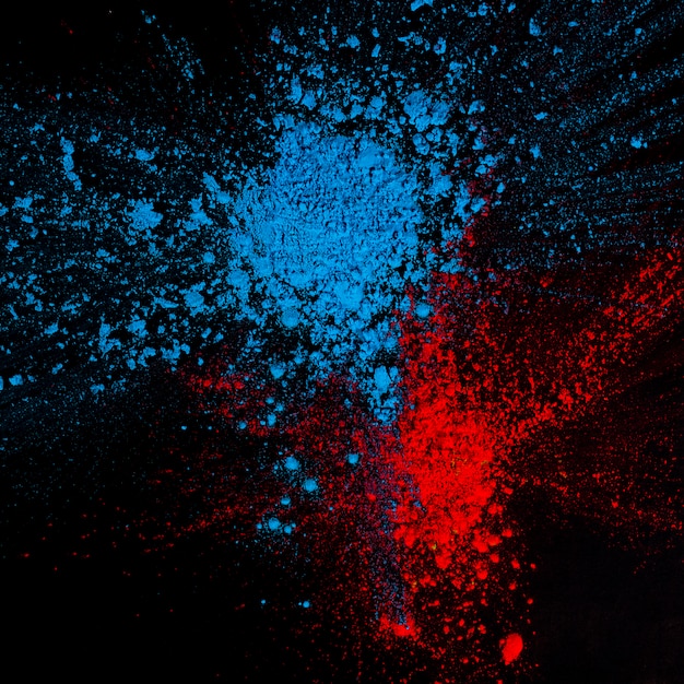 Hohe Winkelsicht des roten und blauen besetzten holi Pulvers über schwarzem Hintergrund