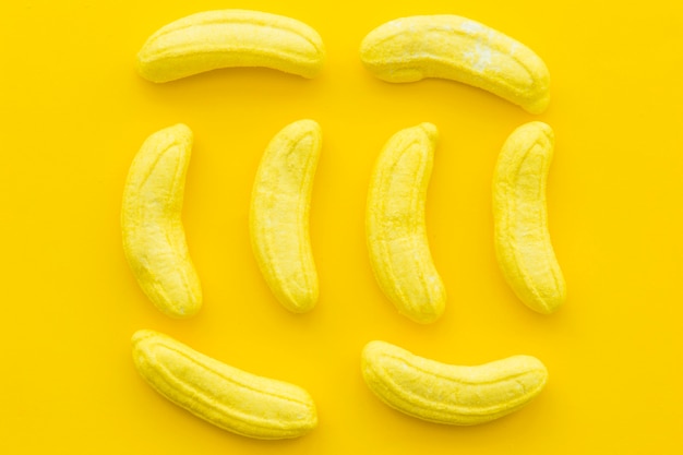 Hohe Winkelsicht von Banane formte Süßigkeiten auf gelbem Hintergrund