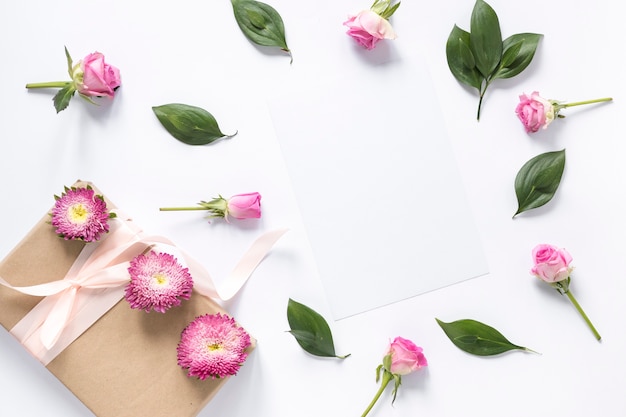 Hohe Winkelsicht von Blumen und von Blättern mit Geschenkbox auf weißer Oberfläche