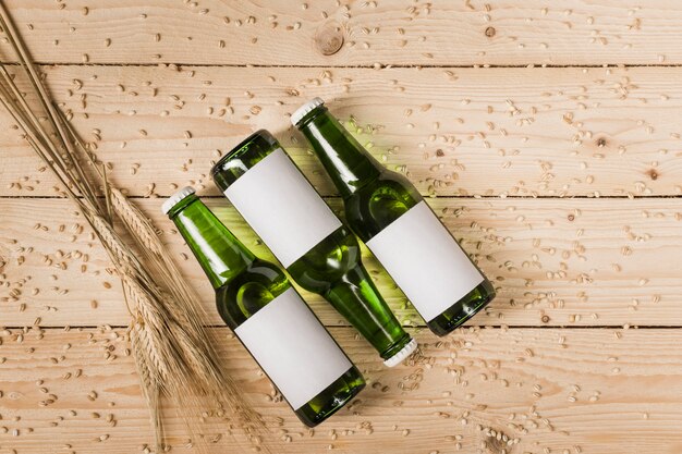 Hohe Winkelsicht von drei Bierflaschen und Ähren auf Woodgrain