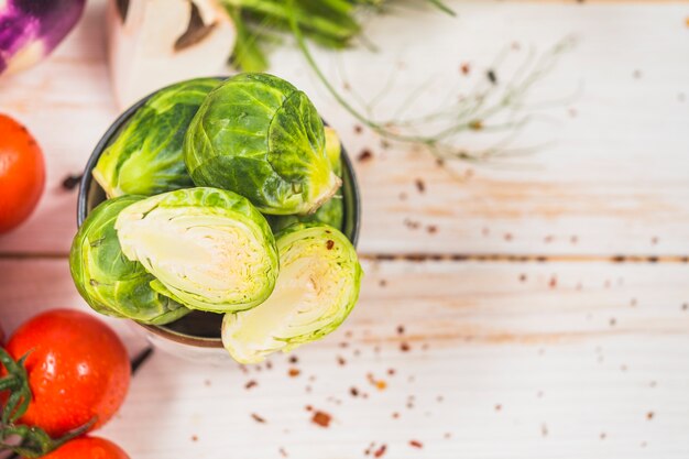 Hohe Winkelsicht von frischem Rosenkohl und von roten Tomaten auf Holztisch