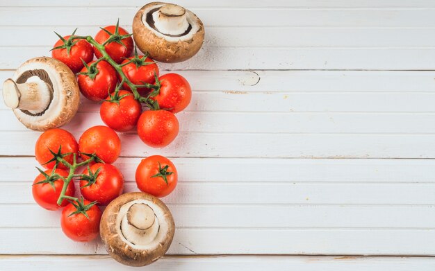 Hohe Winkelsicht von frischen roten Tomaten und von Pilz auf hölzernem Hintergrund
