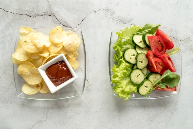 Hohe Winkelsicht von Kartoffelchips mit Soßen- und Gemüsesalat auf Glasschüssel