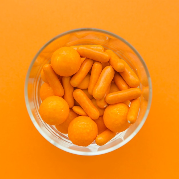 Hohe Winkelsicht von Süßigkeiten in der Schüssel auf orange Hintergrund