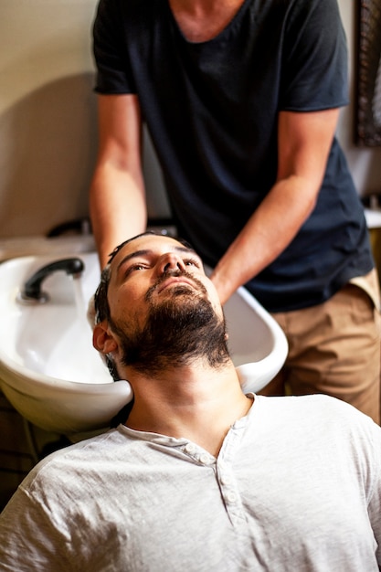 Kostenloses Foto hoher ansichtmann, der eine haarwäsche erhält